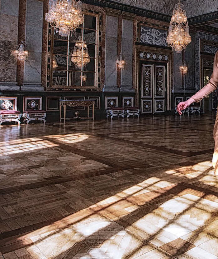 Elegant woman in a gold dress dancing in a luxurious ballroom with chandeliers. photographer NYC