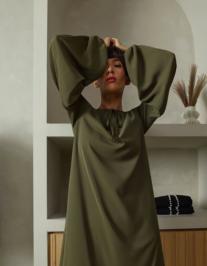 Fashion portrait of a woman in an olive green dress with large sleeves. photographer NYC