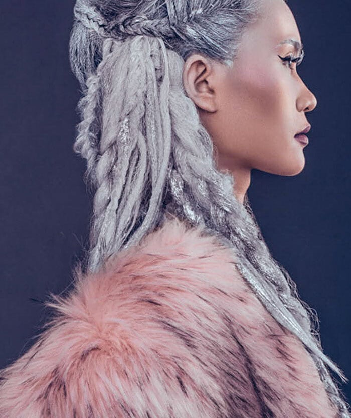 Close profile portrait of a fashion model with silver braided hair and a pink fur coat.